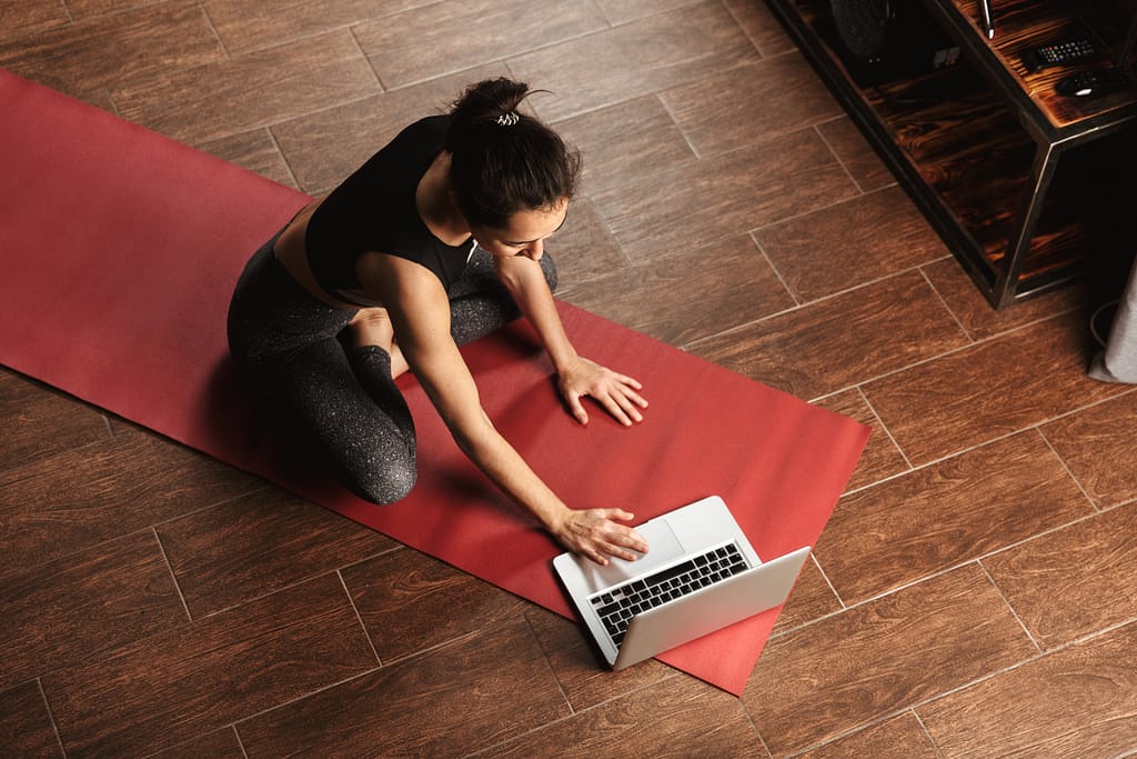 woman sitting on a yoga mat using online services for yoga affirmations