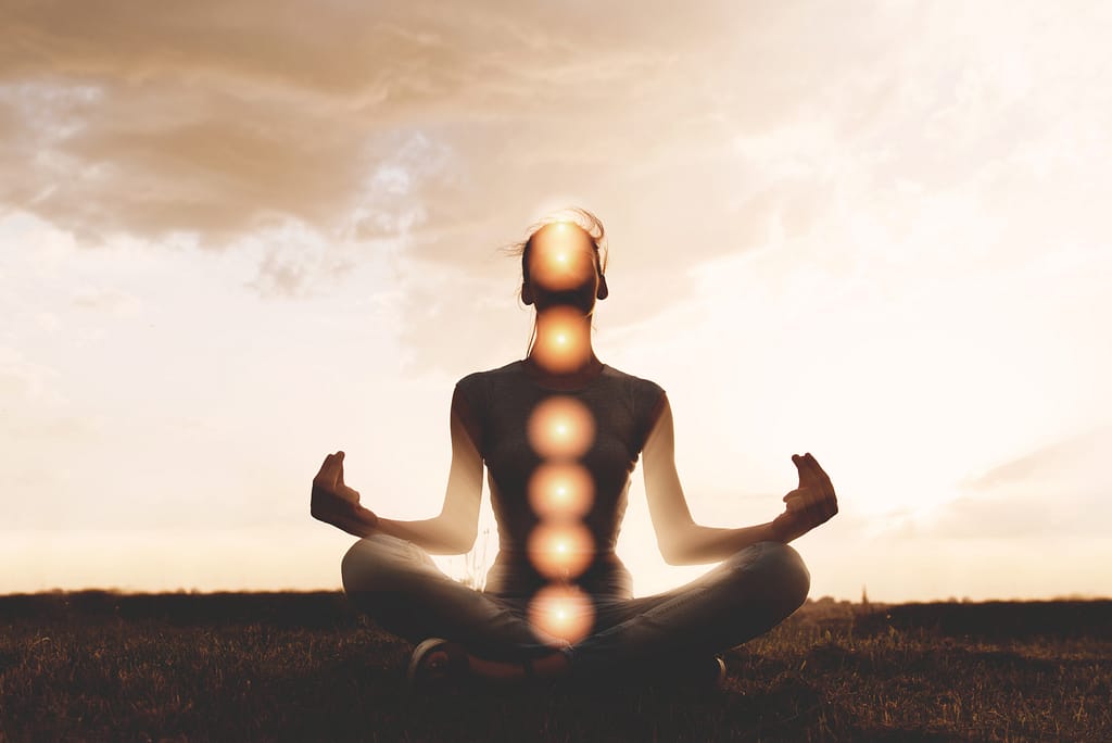 image of a man sitting. all chakras are illuminated by using mudras and mantras