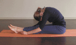 Woman sitting on a yoga Mat doing caterpillar Yin Yoga pose
