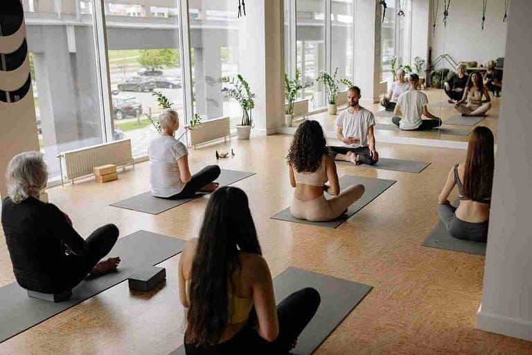 A yoga man at the head of a class-leading a Online Yoga Teacher Training