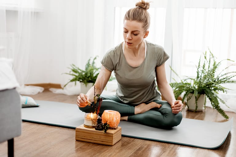 Young relaxed woman doing yoga at home with candles and incense.