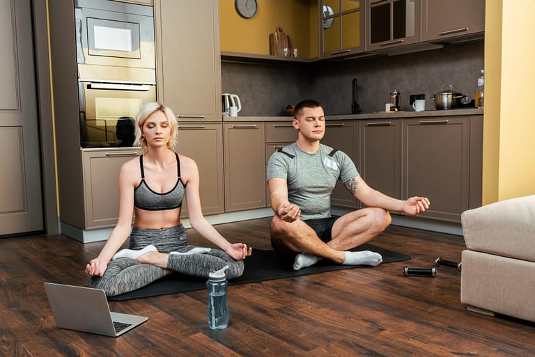 man and woman sitting on the floor on a yoga mat living heart chakra lifestyle practicing heart chakra mantras