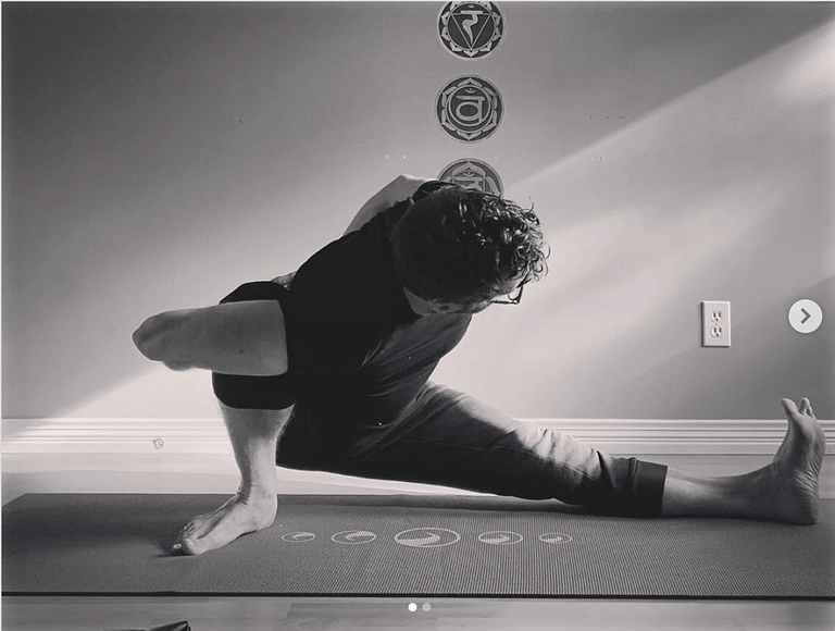 kevin parenteau a man doing a side yoga posture in his home yoga studio