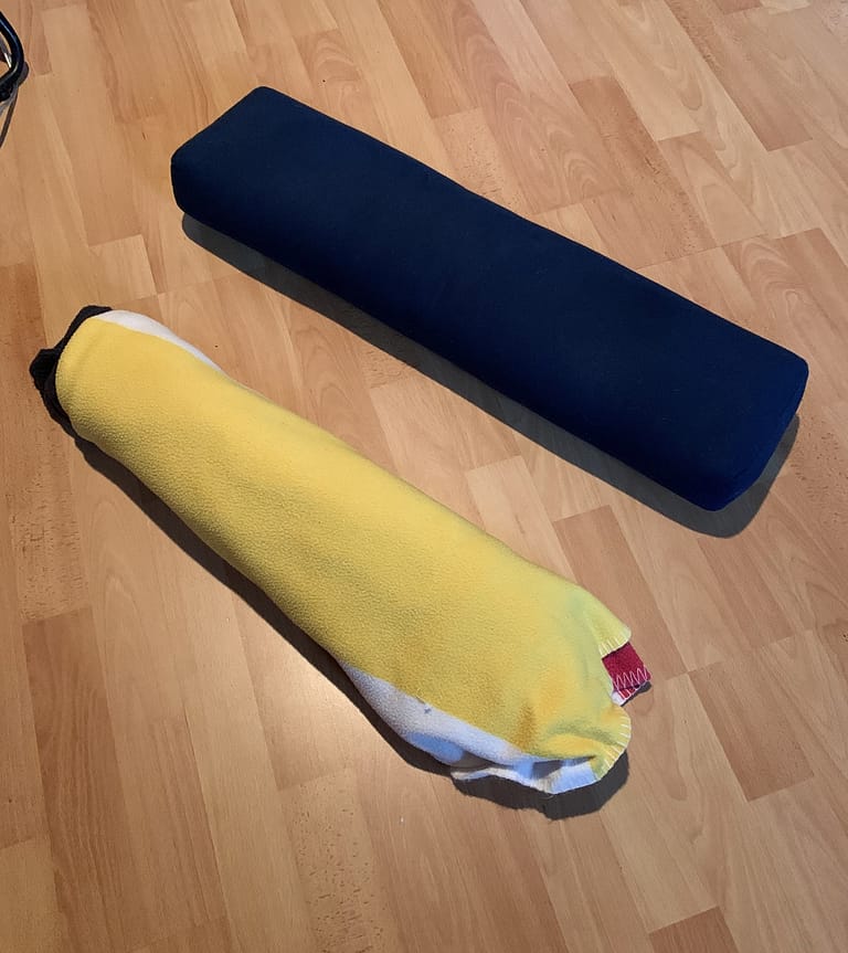 DIY Yoga Prop Blanket rolled up to make DIY Yoga Bolster on Left. Used as a substitute yoga bolster to the Commercial grade yoga bolster on the right.